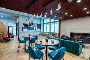 Henderson apartment for rent - a lounge area with blue chairs and tables and a fireplace