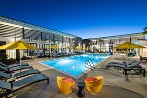 Sacramento apartment for rent - a pool with lounge chairs and umbrellas in front of a building