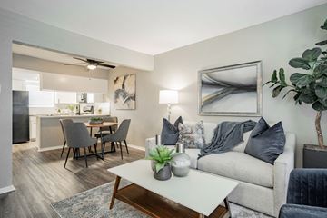 Dallas apartment for rent - A living room with a grey couch, a coffee table, and a dining table with chairs.