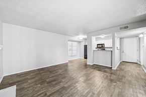 Dallas apartment for rent - A spacious room with wooden flooring and white walls.