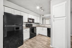 Dallas apartment for rent - A black refrigerator stands in a kitchen with white cabinets and a black stove.