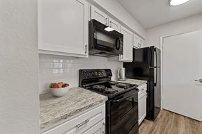 North Richland Hills apartment for rent - a kitchen with white cabinets and black appliances at The Hudson, Texas
