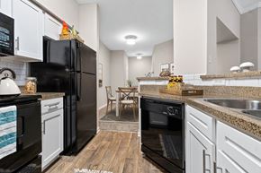 Denton apartment for rent - a renovated kitchen with black appliances and white cabinets at Fountains of Denton in Denton Texas