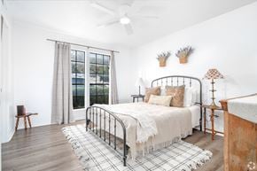 San Antonio apartment for rent - A bedroom with a bed, a chair, and a window with curtains.