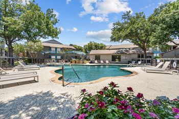 A pool with lounge chairs and trees in the background