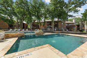 Grapevine apartment for rent - A pool surrounded by trees and a stone wall with the word Vine on it.