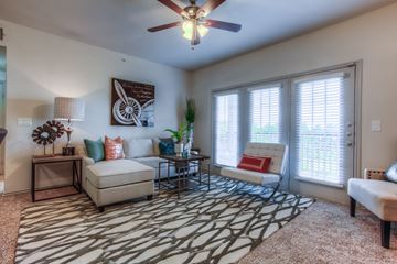 Rowlett apartment for rent - A living room with a patterned rug and a ceiling fan.