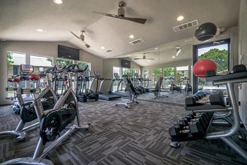 A gym with a lot of exercise equipment and windows