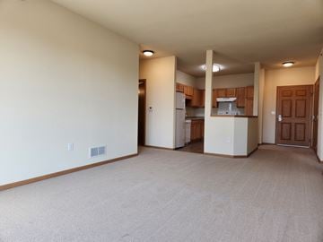 Norwood Young America apartment for rent - A spacious living room with a kitchen in the background.