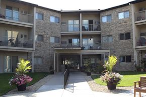 Chaska apartment for rent - A courtyard of apartment buildings with potted plants and a bench.