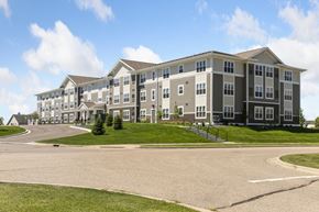 Carver apartment for rent - A large, multi-story apartment building with a parking lot in front.