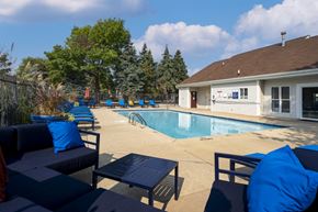 Clinton Township apartment for rent - A pool area with blue cushions and a white building in the background.