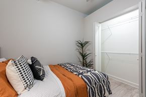 Austin apartment for rent - A bedroom with a bed covered in orange and white bedding and a plant in the corner.