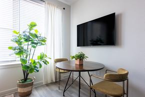 Austin apartment for rent - A living room with a round table, two chairs, a potted plant, and a flat screen TV mounted on the wall.