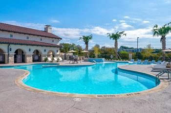 Resort style swimming pool with lounge chairs and palm trees