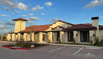 A building with a red tiled roof and a parking lot in front.