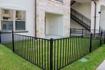 A black metal fence surrounds a white house.