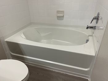 A white toilet sits next to a white bathtub in a bathroom.