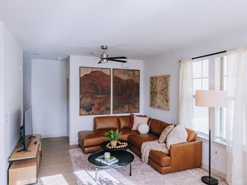 Spring apartment for rent - A living room with a brown leather couch and a painting on the wall.
