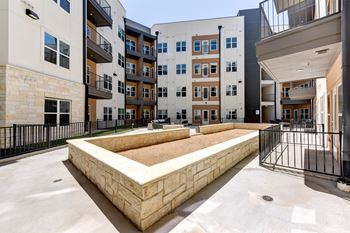 A courtyard with a sandpit surrounded by buildings.