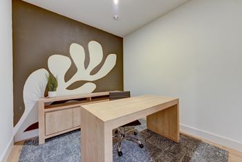 A room with a brown wall and a wooden desk with a plant on it.