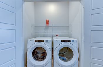 Two washing machines are in a small laundry room.