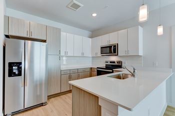 A modern kitchen with a stainless steel refrigerator and a white countertop.