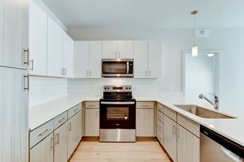 A modern kitchen with a stainless steel oven and white cabinets.