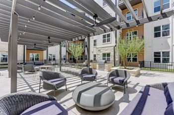 A patio with a white and grey wicker chair and a grey and white cushion.