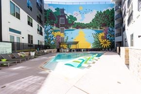 Austin apartment for rent - A mural of a sunny day with trees and a river is painted on the wall above a pool.