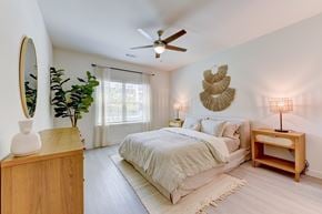 Manor apartment for rent - A bedroom with a bed, a wooden nightstand, and a wooden table with a lamp on it.