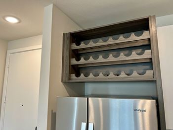 Wall mounted wine rack above stainless steel refrigerator