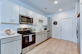Austin apartment for rent - A modern kitchen with white cabinets and a wooden floor. at Park South Apartments, Austin, Texas