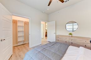 Austin apartment for rent - A bedroom with a bed, dresser, and a mirror on the wall. at Bridge at Speyside Apartments, Austin, Texas