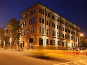 Baltimore apartment for rent - A long building with many windows is lit up at night.