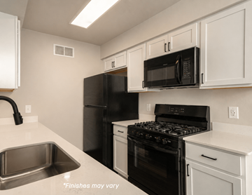Lake Orion apartment for rent - A kitchen with black appliances and white cabinets.