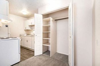 A kitchen with white cabinets and a large closet with shelving