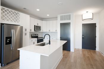A large white kitchen with stainless steel appliances and a white counter top