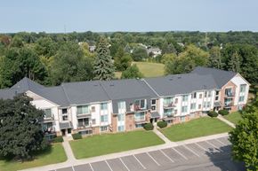 Wixom apartment for rent - A large building with a parking lot in front of it.