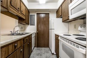 Lafayette apartment for rent - a kitchen with white appliances and wooden cabinets and a refrigerator at Bay Pointe Apartments in Indiana 47909