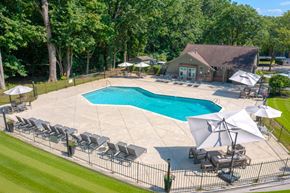 Farmington Hills apartment for rent - A large outdoor swimming pool surrounded by lawn chairs and umbrellas