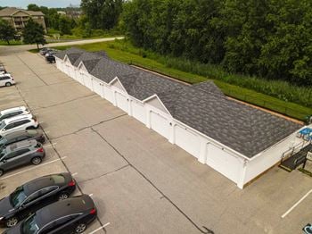 A parking lot with cars and a white building with grey roofs