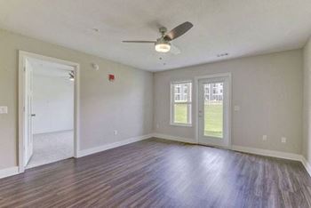 An empty living room with a ceiling fan and hard surface flooring