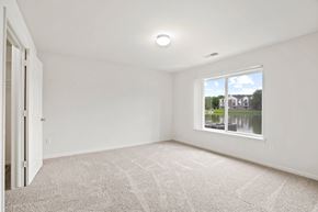 Grand Chute apartment for rent - A room with a carpeted floor and a window showing a view of a house and trees at Towne Lakes Apartments, Grand Chute