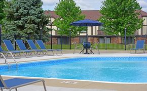 Grand Blanc apartment for rent - Our apartments have a swimming pool with chairs and umbrellas at Thornridge Apartments in Grand Blanc, Michigan
