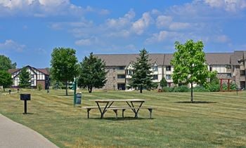 A picnic table in a park in front of an apartment building