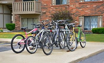 A group of bikes parked on a rack in front of a building