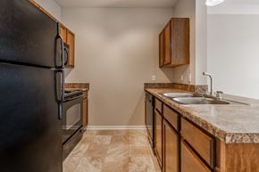 Merrillville apartment for rent - A kitchen with a black refrigerator and brown cabinets