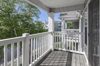 A porch with a white railing and a house in the background
