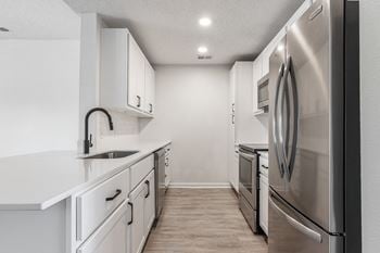 An empty kitchen with white cabinets and stainless steel appliances